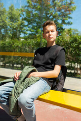 Obraz premium Teenager waiting the bus at the stop in the city