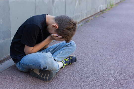 Lonely teenager sitting on the floor outdoors