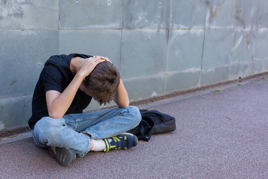 Lonely teenager sitting on the floor outdoors