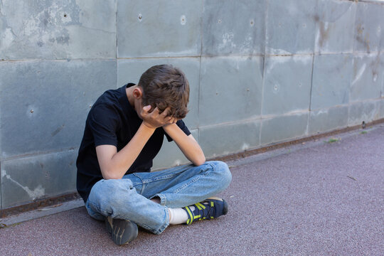 Lonely teenager sitting on the floor outdoors