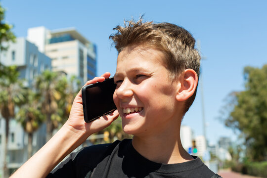 Teenager looking to his phone sitting outdoors