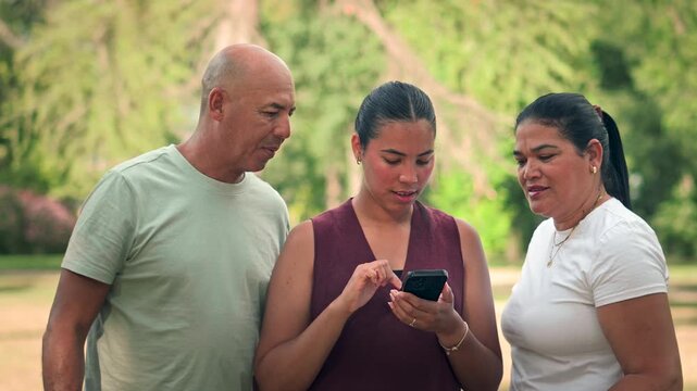 Parents and daughter looking at smartphone together in park slow motion