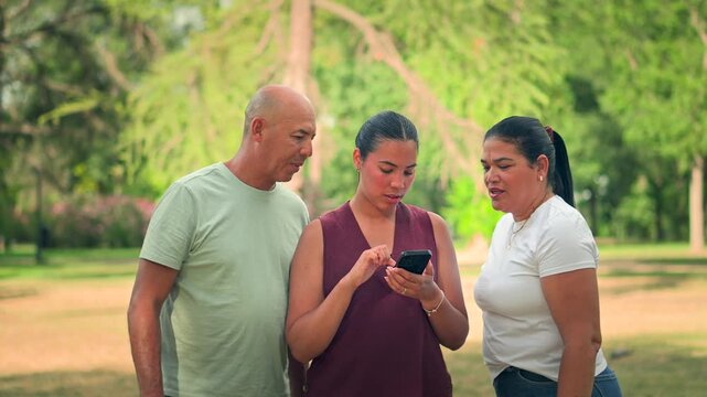 Parents and daughter looking at smartphone together in park