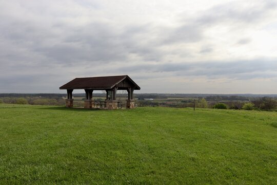 The empty wood picnic shelter in the park on a cloudy day.
