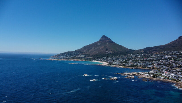 Aerial stock image of Camps Bay, Clifton, Bantry Bay, Bakoven and Lions Head,  Cape town Coastline camera approaching from the sea over the beach and neigbourhood on a summer day
