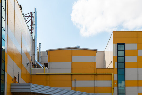 building with a yellow and gray facade that has various industrial elements. The scene presents a blend of architecture and design under a clear blue sky