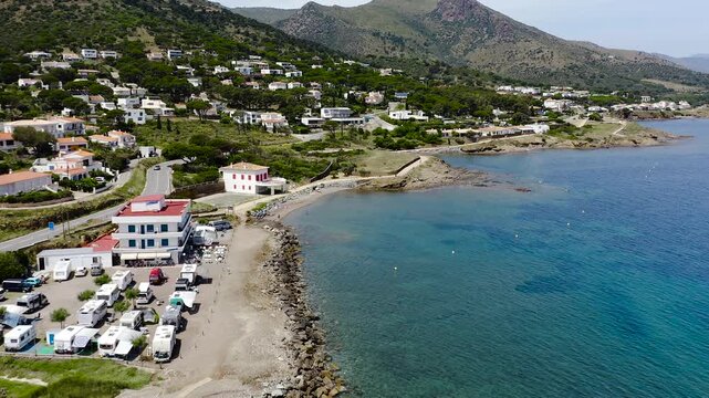 Aerial view of La Vall Beach, the main urban beach of Port de la Selva, with golden sand, calm Mediterranean waters and the village waterfront. 