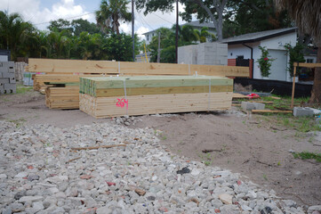 Unfinished cinderblock building at a residential construction site showing concrete block walls, exposed lintels, stacked lumber and gravel forecourt under a blue sky, illustrating building progress a © Del Harper