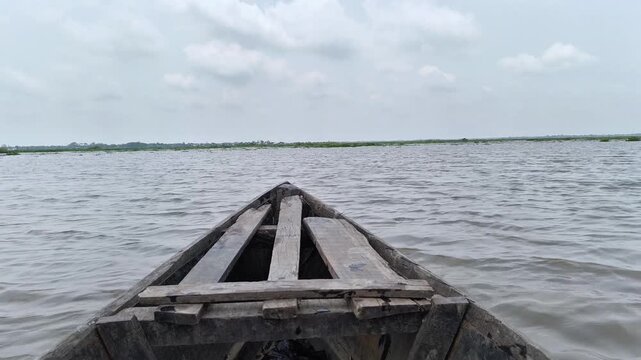 Wooden boat floating on a large body of water with a cloudy sky