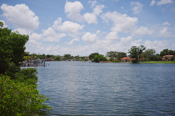 Fototapeta premium Waterfront Neighborhood Across Calm Bay With Palm Trees And Blue Sky Clouds View north from Snell Isle Bridge Coffeepot Bayou in St. Petersburg, FL palm trees and docks beneath a bright blue sky dot