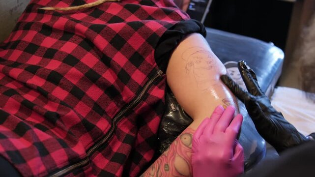 Tattoo artist works on a design in a studio with clients present and tools ready for the session