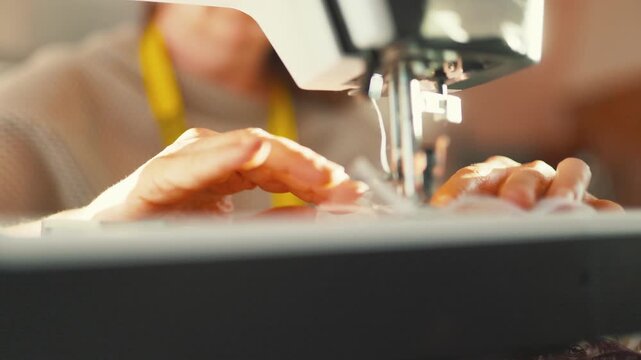 Seamstress hands sewing fabric on machine