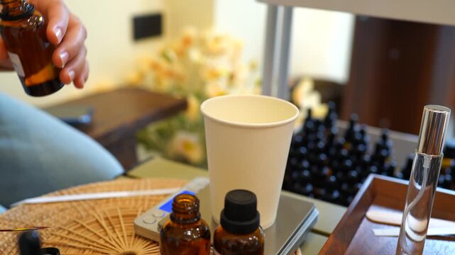Person using a dropper to mix essential oils in a wellness workshop. Aromatherapy preparation, herbal extracts, natural healthcare, cosmetic formulation and holistic treatment concept.