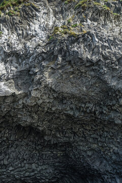 Close-up view of a rugged rock formation with layered textures and moss-covered surface,Reynisdrangar,Iceland