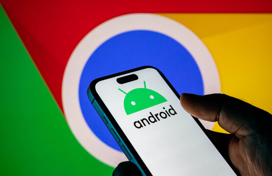 Person holding a smartphone displaying the android logo with the google chrome logo in the background