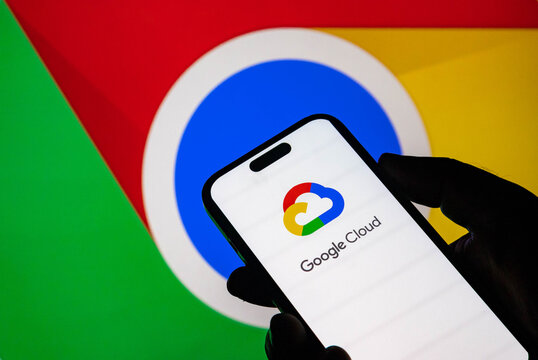 Closeup of a smartphone displaying the google cloud logo with the google chrome browser icon in the background
