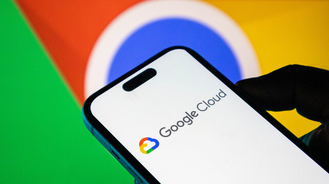 Closeup of a smartphone displaying the google cloud logo with the google chrome browser icon in the background