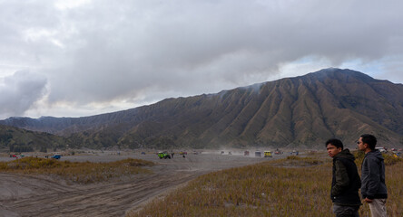 Fototapeta premium Tourists enjoying the vast and dramatic volcanic landscape of Mount Bromo Tengger Semeru, Indonesia.