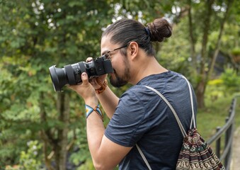 Profile portrait of a man with a hair bun taking photos outdoors © Baudalab