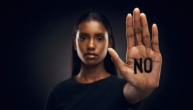 determined female professional making a stop gesture with the word NO on her open palm, representing workplace boundaries, personal safety protection, and social advocacy campaigns.