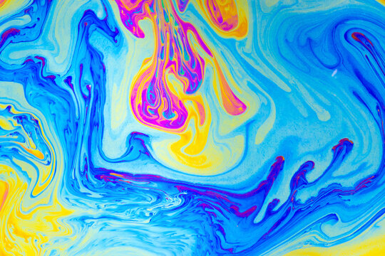 Abstract fluid paint swirl in blue yellow pink pattern with bright smooth wave and marbled texture