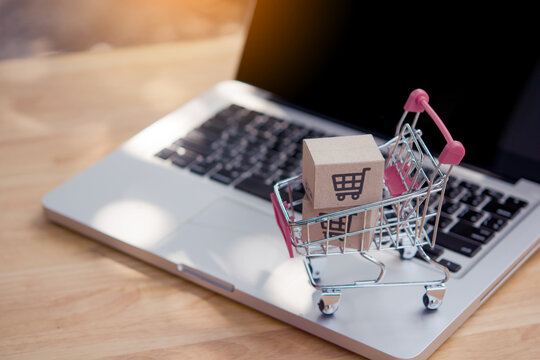 Shopping online. Cardboard box with a shopping cart logo in a trolley on laptop keyboard. Shopping service on The online web. offers home delivery