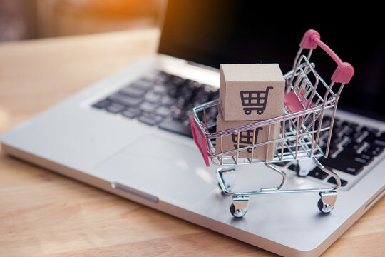 Shopping online. Cardboard box with a shopping cart logo in a trolley on laptop keyboard. Shopping service on The online web. offers home delivery