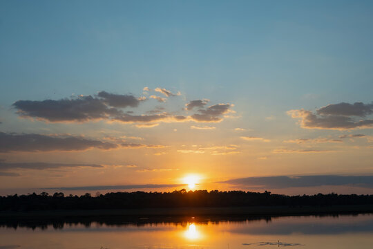 Sunset over calm lake with cloudy sky and reflected light