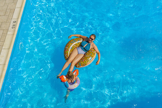 Child girl and mother in swimming pool. Having fun on vacation at the hotel pool. Colorful vacation concept.
