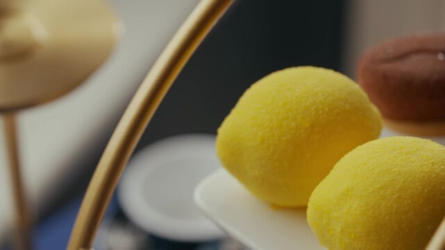 Yellow and brown dessert spheres on a white plate for afternoon tea