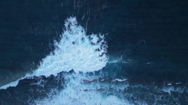 This aerial view shows the crashing waves breaking against the shore from a descending top view. Watch the waves roll and fall