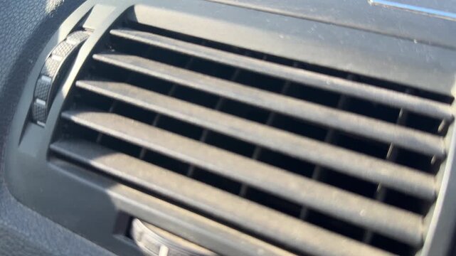 Close-up of horizontal air vent slats on a car dashboard, adjustable ventilation control, vehicle interior, automotive climate equipment.