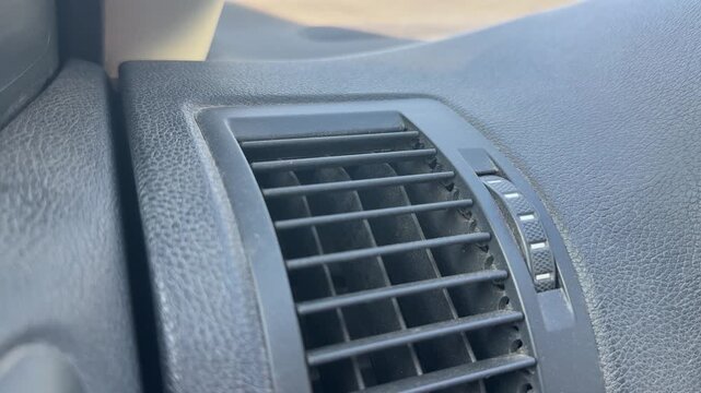 Close-up of a rectangular side air vent recessed in a textured car dashboard, adjustable airflow control, vehicle interior, climate system.