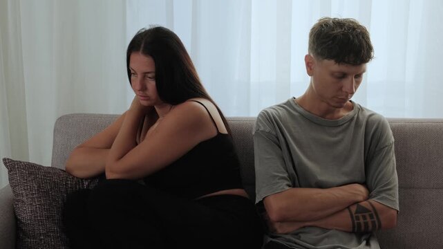Relationship Conflict. Young couple sitting apart on sofa after disagreement, emotional disconnection, unresolved issues, relationship tension, communication problems, modern couple struggle at home