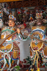 Fototapeta premium Two monumental, highly detailed statues of the Buddhist Heavenly Kings (Lokapala) guarding a temple hall at the Daxingshan Temple complex in Xi'an, Shaanxi Province, China,
