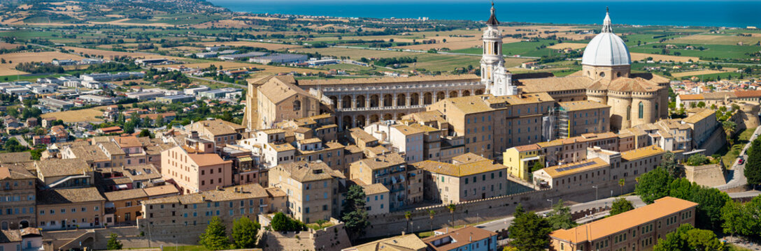 Loreto Sanctuary drone panoramic view in Marche Italy with sea. Cinematic aerial of Holy House Basilica dome and historic medieval defensive walls against blue Adriatic coast horizon.