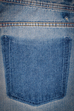 Close up view of a blue denim fabric showing the back pocket area of jeans during daylight