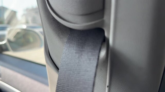Seat belt strap is pulled and slides through the side pillar guide inside a car, restraint movement, passenger safety, vehicle interior.