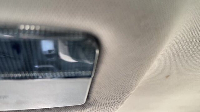Interior dome light turns on and off inside a car, close-up of the ceiling lamp, cabin illumination, vehicle control, automotive convenience.