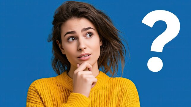 Young pensive woman in yellow sweater touching chin with hand thinking with big question mark on solid blue background representing uncertainty and question concept