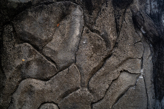 Detailed texture of dark grey weathered concrete wall with organic cracked stone look patterns