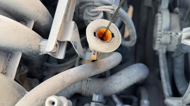 Engine oil dipstick is pulled from its tube during a car maintenance check, fluid inspection, automotive service, engine care, mechanical diagnosis.