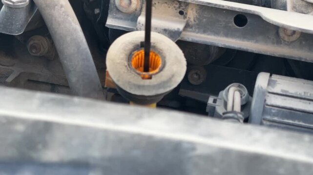 Engine oil dipstick moves inside its tube during a vehicle fluid level check, routine car maintenance, automotive inspection, mechanical service.