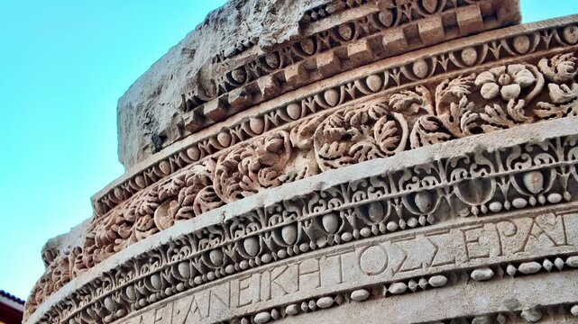 Intricate ancient roman stone carving with floral patterns and greek inscription.
