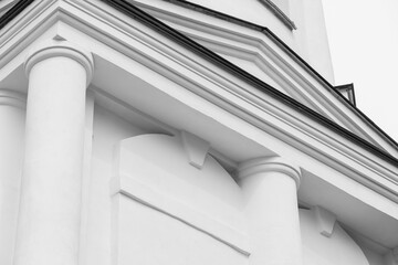 Naklejka premium White classical building facade with round columns and pediment showcasing architectural detail in a high-contrast black and white composition, emphasizing symmetry, texture, and historic design