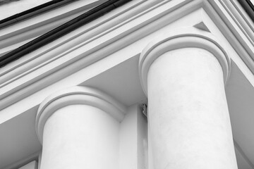 Naklejka premium White classical building facade with round pillars and pediment showcasing architectural detail in a black and white composition, emphasizing style, texture, and historic design