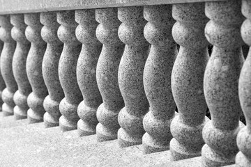 Naklejka premium Elegant stone balustrade featuring repeating turned granite columns that create rhythmic texture and symmetry in black-and-white architectural photography