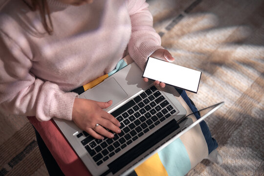 Woman using smartphone and laptop at home &ndash; remote work, online communication and digital lifestyle.