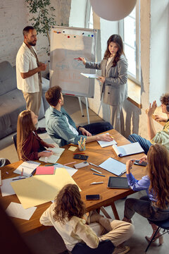 Female business leader presenting strategy board to creative team. Concept of leadership presentation, team coaching, business education, strategy workshop, workplace communication.