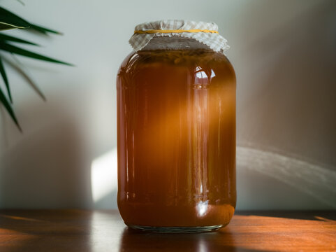 Kombucha Brewing Process in a Glass Jar on a Wooden Table